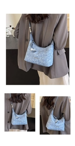 Detail view of denim shoulder bag featuring silver JINGPIN metal plate and beaded charm
