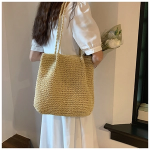 French style straw tote bag worn by model in a white dress for a summer beach look