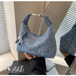 Detail of blue denim hobo bag featuring quilted stitching and silver metal logo lettering