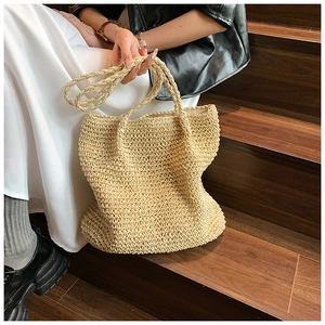 Close-up detail of a beige woven straw tote bag with dual handles and long shoulder strap