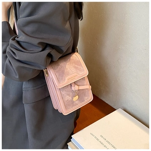 Detail of light pink mini leather crossbody bag with suede flap and gold lettering