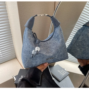 Detail of blue denim hobo bag with metal buckle handle and transparent bead charm