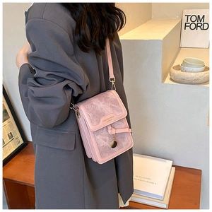 Detail view of pink textured crossbody bag with gold round pendant and slim strap