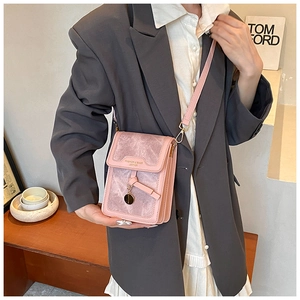 Pink lychee texture crossbody bag with gold metal charm shown in a lifestyle setting