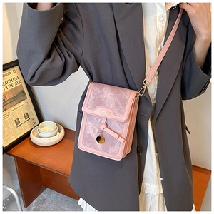 Detail of pink vintage crossbody bag with gold hardware worn by a model in suit