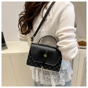 Detalle de bolso bandolera de cuero negro con patrones geométricos azules y hebilla