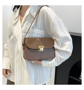 Detail of vintage brown leather crossbody bag with a square golden metallic lock buckle