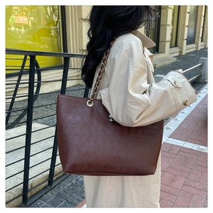 Détail du sac cabas marron foncé avec motif tête de mort et bandoulière en chaîne