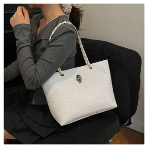 Gros plan d'un sac cabas blanc en cuir avec reliefs de crânes et détails métalliques