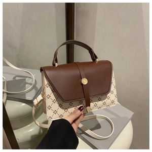 Detalle de bolso vintage con solapa de cuero marrón y elegante diseño floral