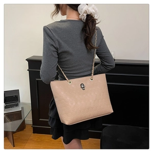 Detail of gothic beige tote bag with skull embossing and metal hardware on shoulder