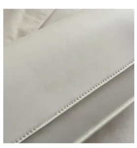 Détail du cuir grainé et du logo doré FASHION & BAGS sur un sac baguette blanc chic