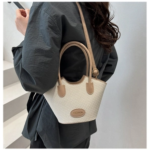 Detail einer geflochtenen Beuteltasche mit khakifarbenem Lederbesatz und Schultergurt