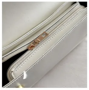 Gros plan d'une fermeture éclair en métal doré clair sur un sac baguette en cuir blanc
