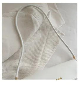 Détail des finitions dorées et de la bandoulière en cuir d'un sac à main blanc