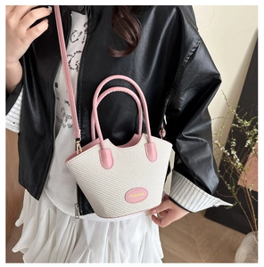 Detail der gewebten Strohtasche mit rosa Ledergriffen und abnehmbarem Schultergurt