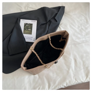 Détail du sac cabas beige matelassé avec motif en relief et bandoulière en chaîne dorée