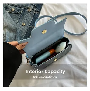 Internal capacity of minimalist denim crossbody bag showing phone and cosmetics
