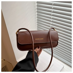 Detail of dark brown leather underarm bag with gold logo and metallic strap buckle