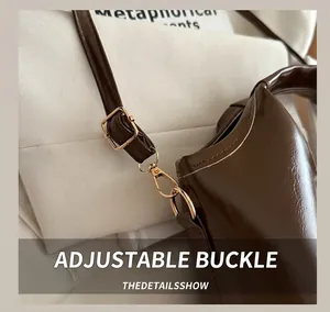 Detail of adjustable shoulder strap with gold hardware on a brown leather bucket bag