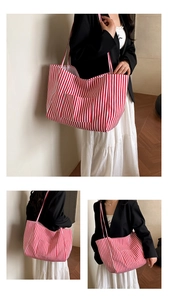 Detail of red and white striped canvas tote bag showing the front pocket and large capacity