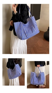 Detail of blue and white striped canvas tote bag showing the front pocket and dual straps