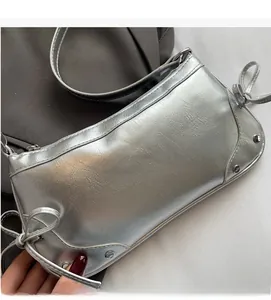 Close-up of metallic silver shoulder bag with side bow drawstring and rivet details