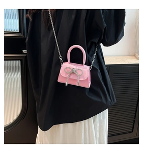 Detail of pink patent leather mini bag featuring a large sparkling crystal bow decoration