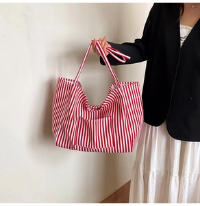 Close-up of red and white striped canvas tote bag featuring a front pocket and handle