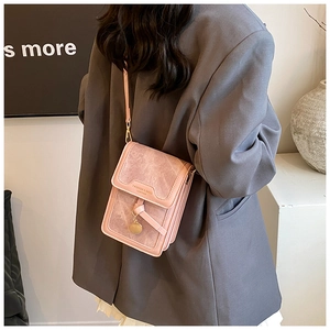 Pink leather crossbody bag with metal charm detail shown as a lifestyle back view