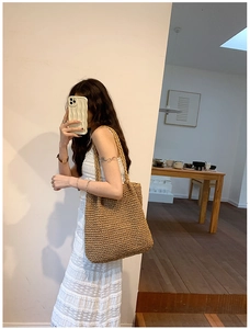 Detail view of large straw tote bag featuring thick woven texture and sturdy shoulder handle