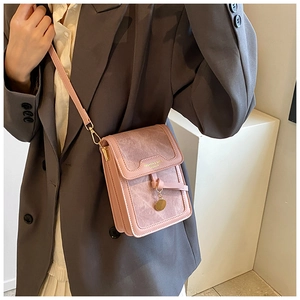 Close-up of pink leather crossbody phone bag with gold pendant on a grey suit jacket