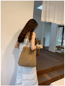 Detail of hand-woven straw shoulder bag showing dense crochet texture on a female model