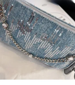 Detail of light blue denim bag with silver sequins and crystal chain strap