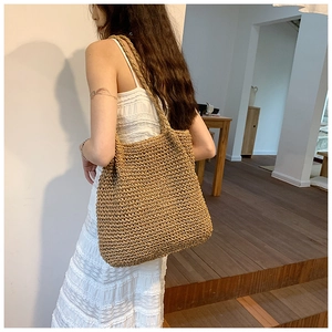 Detail of hand-woven straw tote bag with dense texture and shoulder strap for beach use
