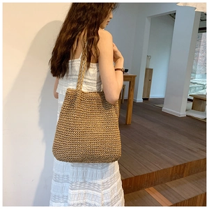 Straw tote bag detail showing large capacity and natural hand-woven texture on model