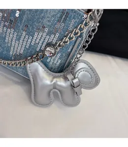 Close-up of a silver dog-shaped charm on a blue denim bag with metallic sequins