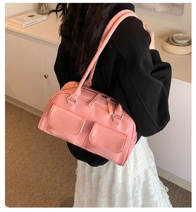 Pink patent leather rectangular shoulder bag with front pockets on a model's shoulder