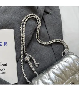 Gros plan sur un sac en cuir argenté matelassé avec bandoulière chaîne et boucle métal