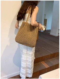 Detail view of woven straw tote bag with textured knit pattern and large shoulder strap