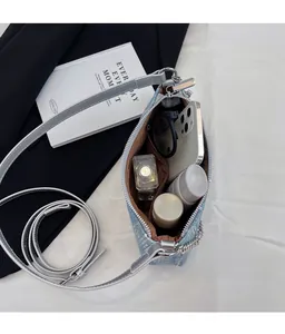 Spacious interior of a light blue denim crescent bag showing phone and cosmetics