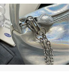 Macro detail of holographic silver underarm bag with high-shine metallic chain hardware