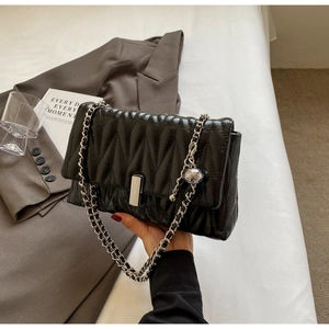 Détails du sac matelassé noir avec bandoulière chaîne argentée et breloque boule en métal