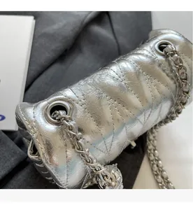 Détail du sac argenté matelassé avec chaîne métallique et pendentif boule brillant