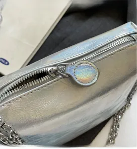 Close-up of smooth metal zipper and silver iridescent crinkle texture on handbag