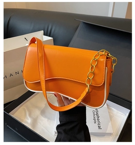 Detail der leuchtend orangen Baguette-Tasche mit weißen Paspeln und goldener Kette