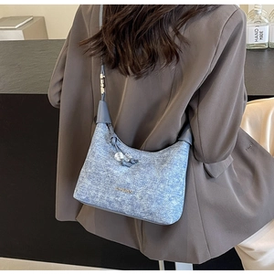 Blue denim quilted bag with Jingpin logo and tassel worn on a brown blazer outfit