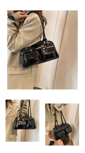 Detail of glossy black patent leather shoulder bag with vintage dual front pockets and silver buckles