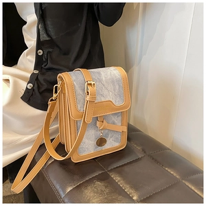 Detail of blue denim and tan leather crossbody bag with gold hardware worn by model