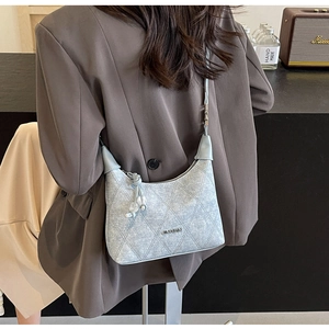 Detailed view of light blue quilted denim shoulder bag with silver logo on casual suit